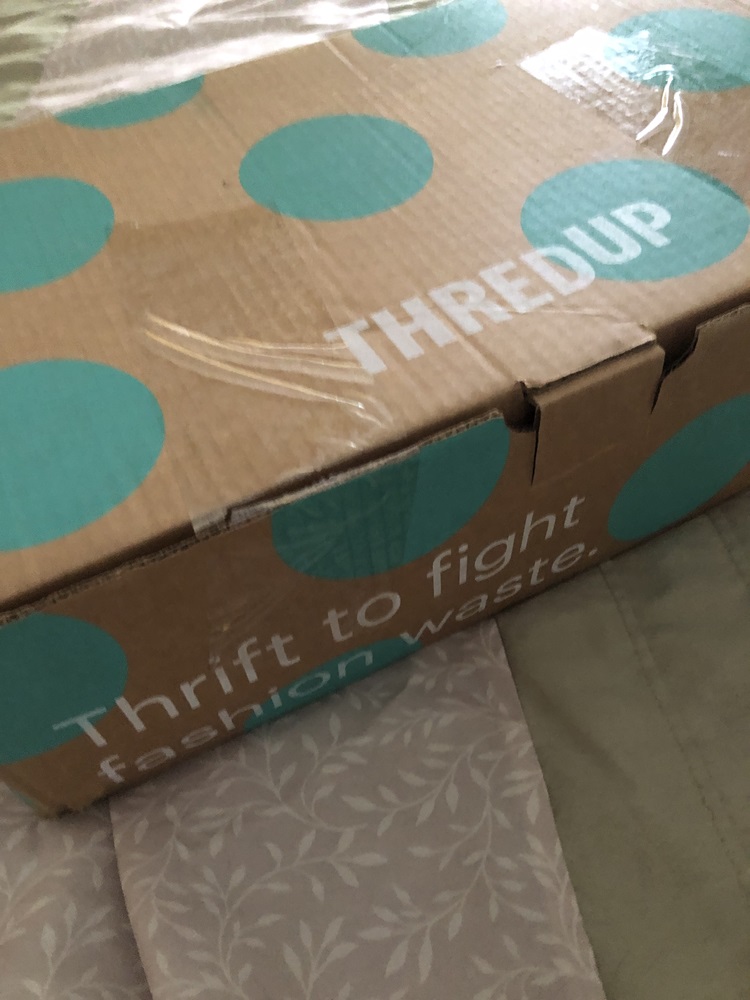 ThredUp box, brown box with turquois dots with the ThredUp logo and "Thrift to fight fashion waste"